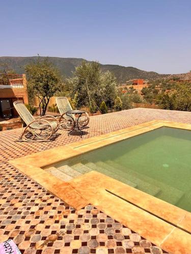 a swimming pool with two chairs and a table at Dar Khalti - Cascades - Piscine - Montagne in Ouzoud
