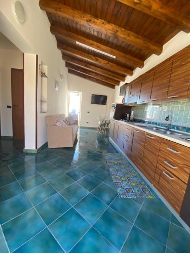 a large kitchen with blue tile floors and wooden cabinets at Villa Ale in Lampedusa