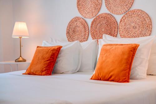 Cama blanca con almohadas de color naranja y blanco en Chalet D´Ávila Guest House en Lisboa