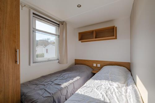 Duas camas num pequeno quarto com uma janela em Mobil Home Manon em Fréjus