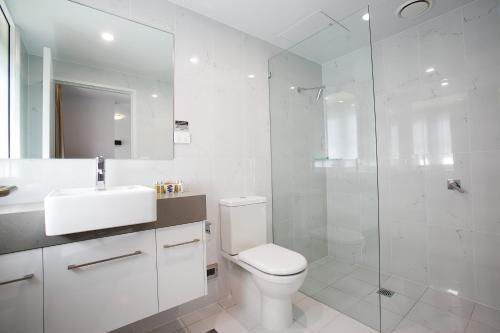 a white bathroom with a toilet and a glass shower at The Lucky Hotel in Newcastle