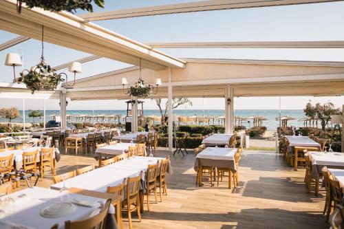 a restaurant with tables and chairs with the ocean in the background at Georgalas Rest Apartments in Nea Kalikratia