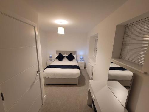 a small bedroom with two beds and a window at New build home with WI-FI, Smart TV, dedicated office floor, large terrace and Free parking in Milton Keynes