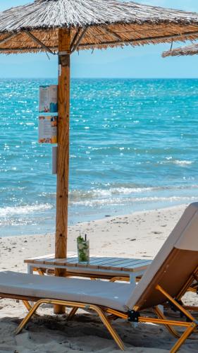 a lounge chair and an umbrella on the beach at Georgalas Rest Apartments in Nea Kalikratia