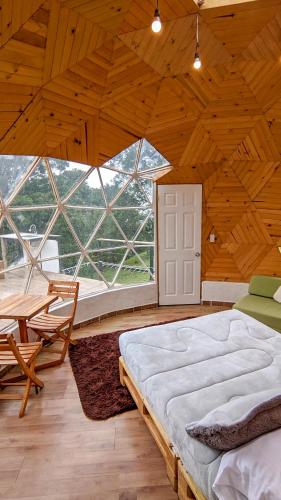a large room with a bed and a large window at Glamping Reserva del Roble in La Vega