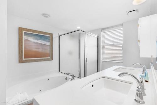 La salle de bains blanche est pourvue d'un lavabo et d'un miroir. dans l'établissement Pelican Beach Resort 501, à Destin