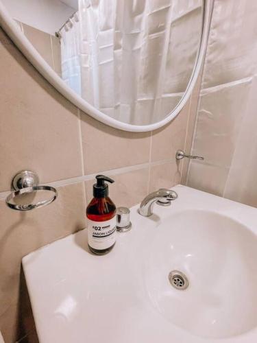 - un lavabo dans la salle de bains avec une bouteille de savon dans l'établissement Espectacular departamento a metros del mar, à Puerto Madryn