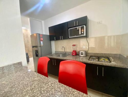- une cuisine avec un comptoir et des chaises rouges dans l'établissement Casa Aliisa, à Mérida