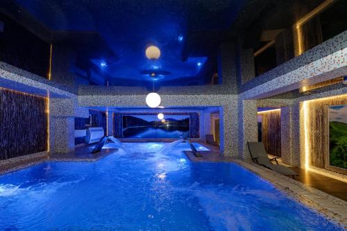 Marmaros Apart-Hotel & Spa في بوكوفِل: مسبح كبير في بيت فيه انارة زرقاء