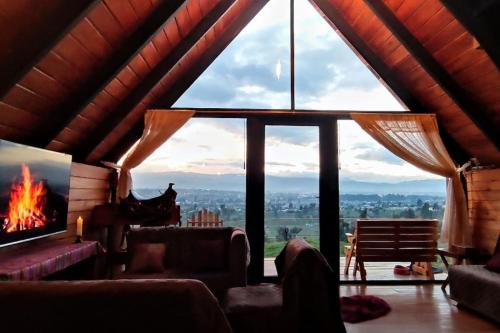 a living room with a fireplace and a large window at Alpina Glamping en Latacunga in Saquisilí