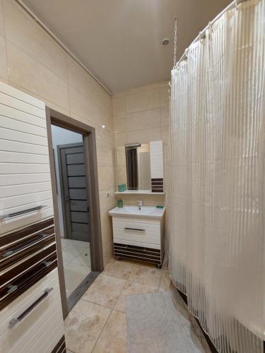 La salle de bains est pourvue d'une douche, d'un lavabo et d'un miroir. dans l'établissement Шикарні апартаменти поруч з Майданом, à Kiev