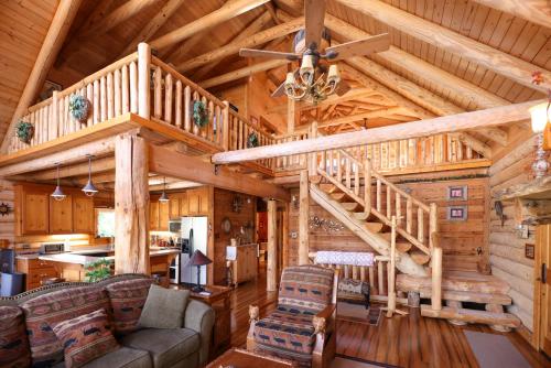una sala de estar con una escalera en una cabaña de madera en Beautiful River-Front Log Cabin Near Williamsburg en Toano
