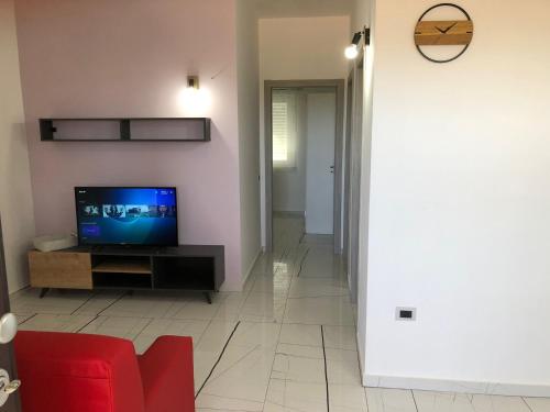 Casa vacanze Capo Rizzuto 3 في Ovile la Marinella: غرفة معيشة مع تلفزيون وأريكة حمراء