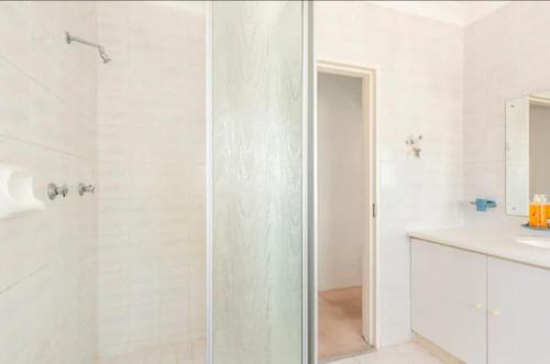 a white bathroom with a shower and a sink at Revive Haven Guesthouse in Roodepoort