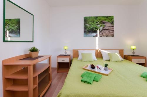 a bedroom with a green bed with a desk and a table at Apartments Ester in Funtana
