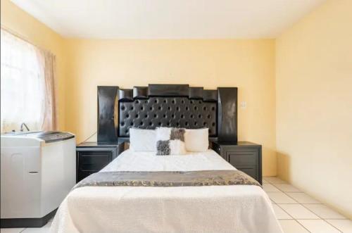a bedroom with a large bed with a black headboard at Revive Haven Guesthouse in Roodepoort