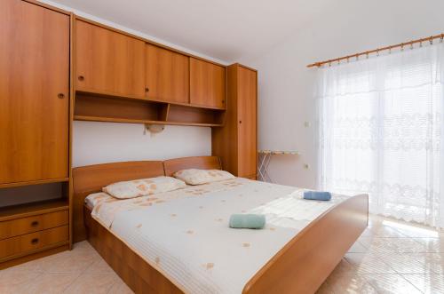 a bedroom with a large bed with a wooden cabinet at Apartment Marija Durdica in Lopar