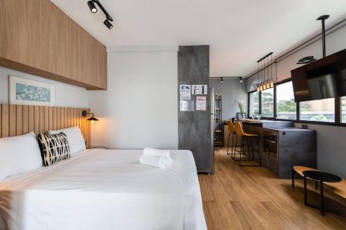 1 dormitorio con 1 cama blanca grande y cocina en Condomínio de studios completos por temporada na Av. Rebouças, en São Paulo