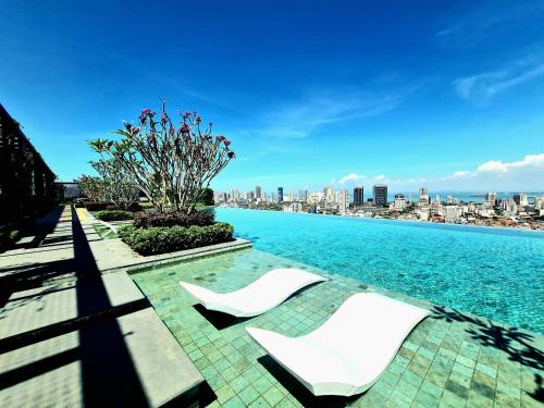 een zwembad met witte stoelen en een skyline van de stad bij Beacon Executive Suites - Penang in George Town