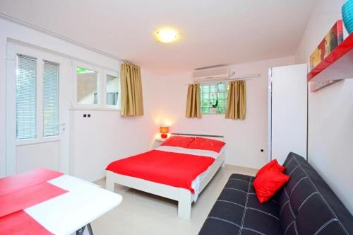 een slaapkamer met een rood bed en een bank bij Apartments Ivan Marina in Krk