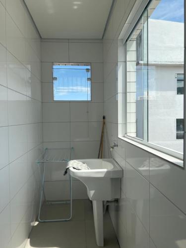 baño blanco con lavabo y ventana en Pousada Suites Enseada Guaruja, en Guarujá