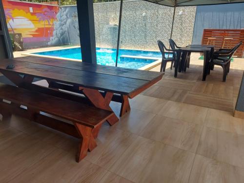 a wooden table and chairs and a swimming pool at Casa com Piscina e 3 Quartos Climatizados 8km do Centro in Palmas