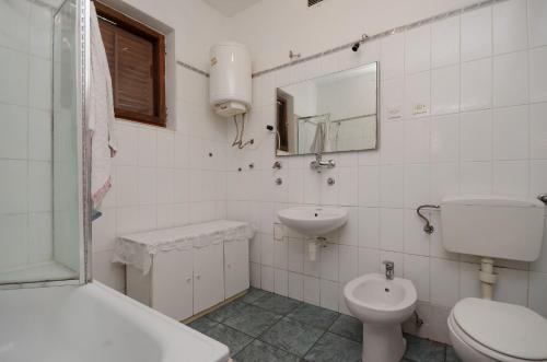 a white bathroom with a toilet and a sink at Apartments Petra in Crikvenica