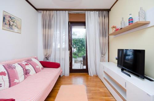 een woonkamer met een bank en een flatscreen-tv bij Apartments Ivanka in Krk