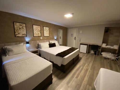 a hotel room with two beds and a desk at Navega Beach Palace Hotel in Navegantes