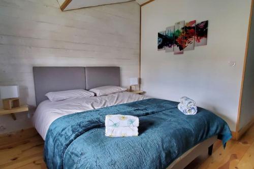 1 dormitorio con 1 cama grande con manta azul en Gîte Rouge Safran pour 4 personnes, en Marsac-en-Livradois