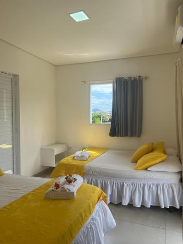 Duas camas num quarto com uma janela em Pousada Suites Enseada Guaruja no Guarujá