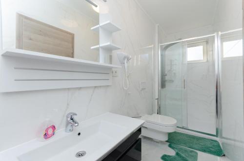 een witte badkamer met een toilet en een douche bij Apartments Darko in Rab