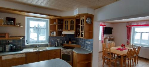 a kitchen with wooden cabinets and a table and a dining room at Chalupa Bílá stopa - celá chalupa pro jednu partu in Stará Ves