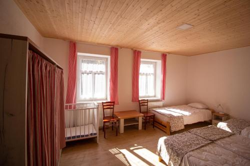 a bedroom with two beds and a crib and two windows at Chalupa Bílá stopa - celá chalupa pro jednu partu in Stará Ves