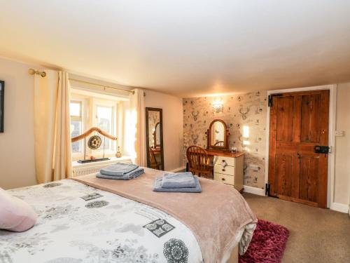 a bedroom with a bed and a dresser and a mirror at Hen's Cottage in Chippenham