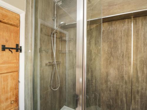 a shower with a glass door in a bathroom at Hen's Cottage in Chippenham