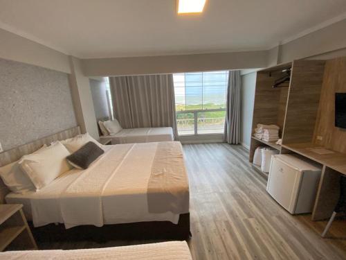 a bedroom with a large bed and a large window at Navega Beach Palace Hotel in Navegantes