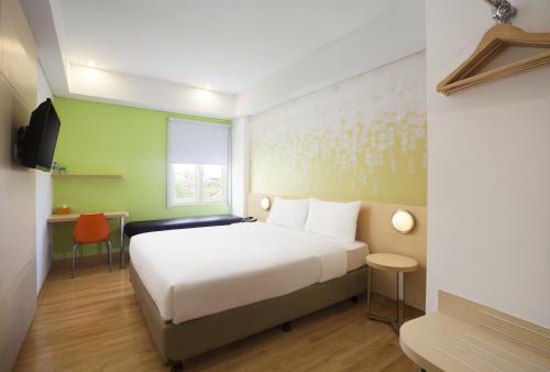 1 dormitorio con cama blanca y pared verde en Zest Yogyakarta by Swiss-Belhotel International, en Yogyakarta