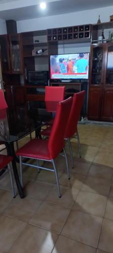 a dining room with red chairs and a television at Casa Privada Monte Grande y cochera in Monte Grande