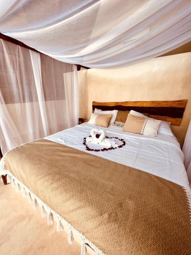 a bedroom with a large bed with a canopy at Lodge Tzunum Jade in Tulum
