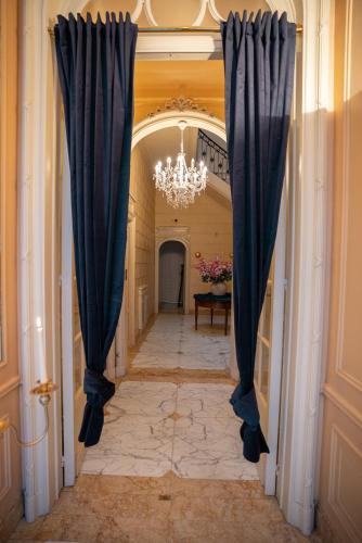 a hallway with blue curtains and a chandelier at Hotel de Maître de Vaughan in Brussels