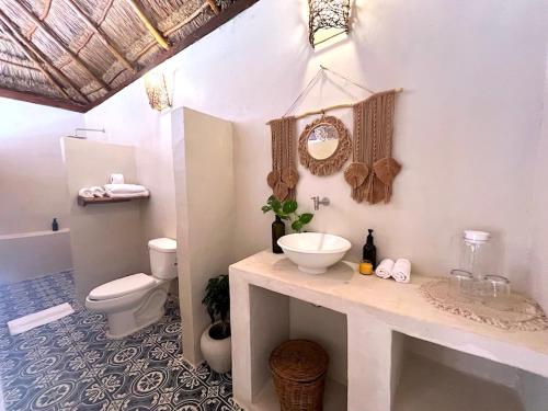 a white bathroom with a sink and a toilet at Lodge Tzunum Jade in Tulum
