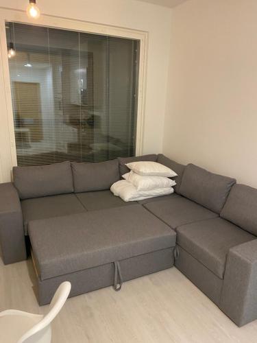a couch in a living room with two pillows on it at Ihana huoneisto juna aseman vieressä. in Vantaa