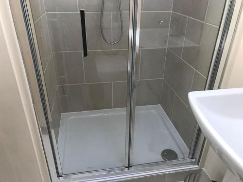 una ducha con una puerta de cristal junto a un lavabo en Self contained studio with own front door en Nazeing