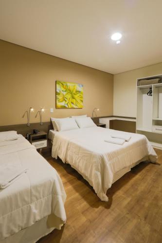 a bedroom with two beds and a painting on the wall at Hotel Itapema in Valinhos