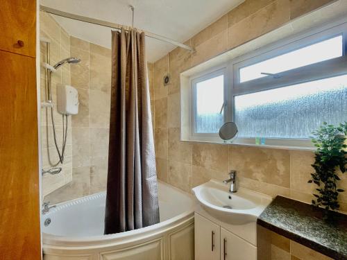 uma casa de banho com uma banheira, um lavatório e uma janela em Tranquil Rentals - Large 4 BDR Home, 3 Bathrooms, Free Parking, Monthly Discounts em Oxford