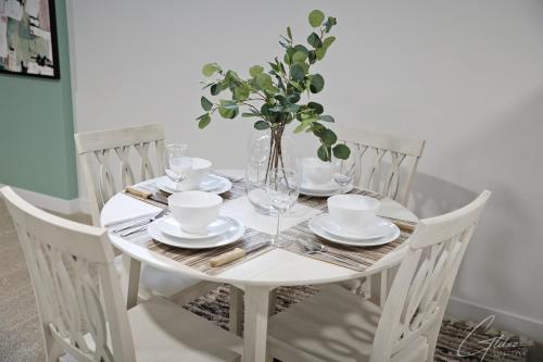 a white table with plates and glasses and a vase at King Bed,Disney,Long Stays,Garage,Airport in Edmonton