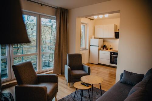 een woonkamer met een bank en stoelen en een keuken bij JBHotels Apartament Premium Plus in Szczecin