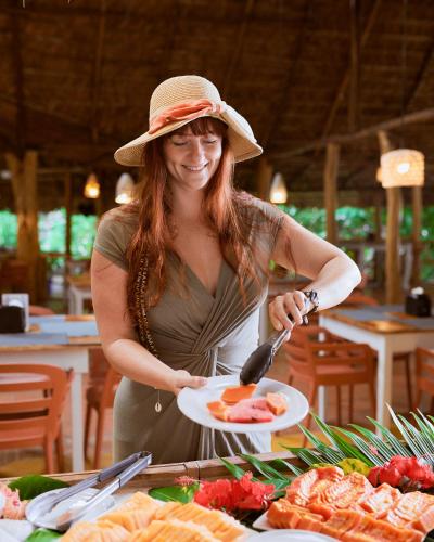 a woman in a hat holding a plate of food at Cariblue Beach and Jungle Resort in Puerto Viejo