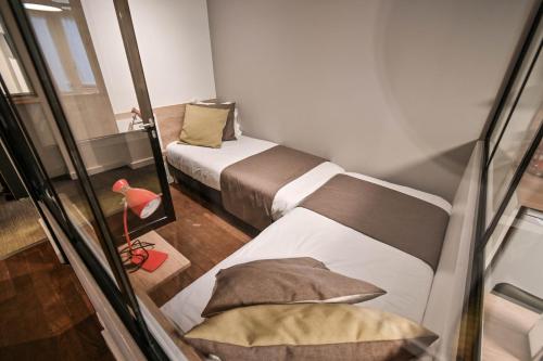 a small room with two beds and a window at Les cles du 27 Paris in Paris
